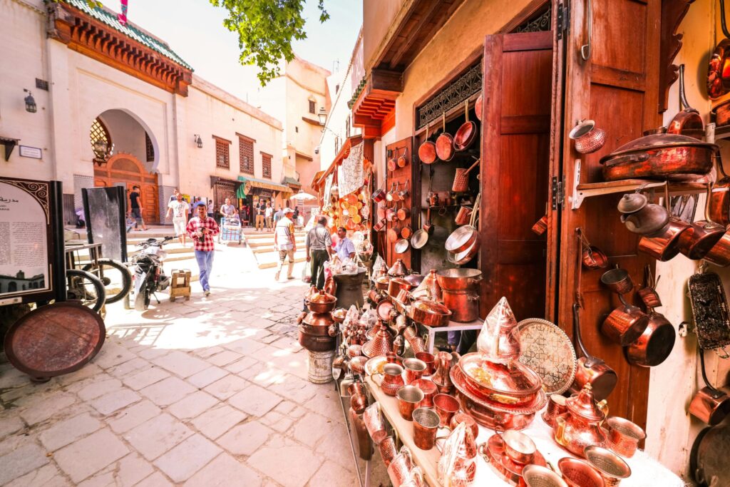A bustling Moroccan street market showcasing copper goods in a vibrant medina setting.
